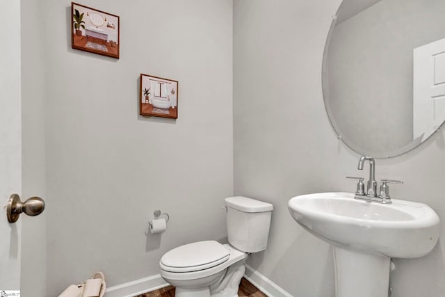 bathroom with a sink, wood finished floors, toilet, and baseboards