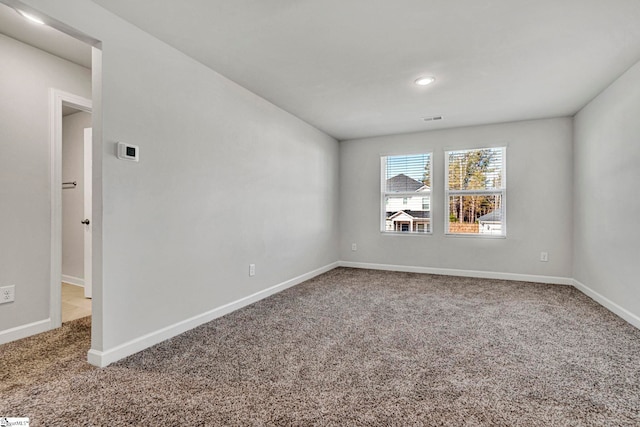 carpeted spare room with visible vents and baseboards