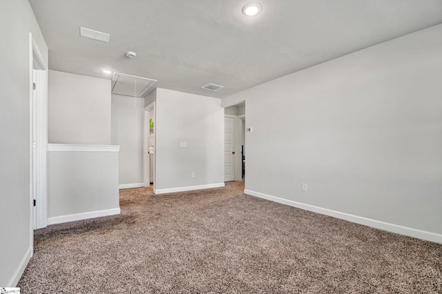 carpeted spare room with attic access, visible vents, and baseboards