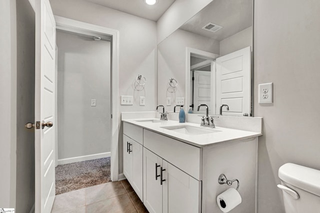 bathroom with visible vents, double vanity, a sink, and toilet