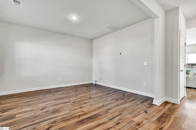 unfurnished room featuring baseboards, visible vents, and wood finished floors