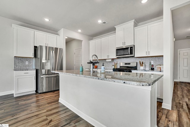 kitchen with a center island with sink, appliances with stainless steel finishes, dark wood-type flooring, white cabinetry, and a sink