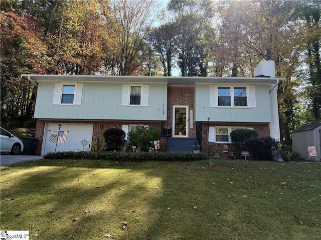 bi-level home with brick siding, an attached garage, a chimney, and a front lawn