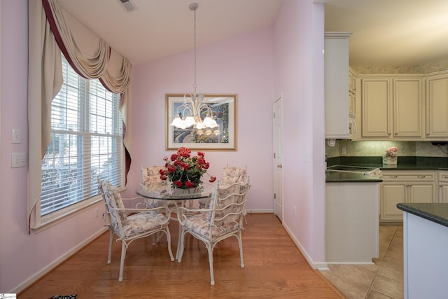 dining area featuring light tile patterned floors, visible vents, baseboards, lofted ceiling, and an inviting chandelier