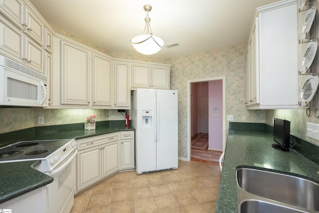 kitchen featuring white appliances, dark countertops, a sink, and wallpapered walls