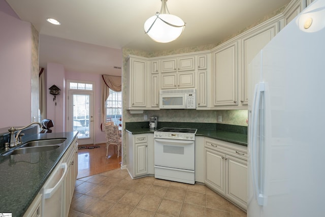 kitchen with light tile patterned floors, white appliances, a sink, and decorative light fixtures