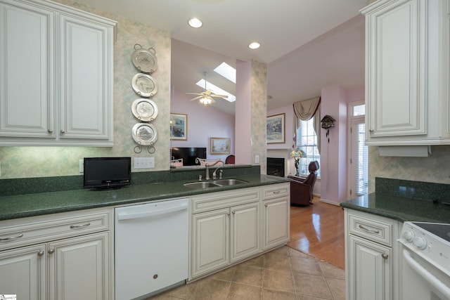 kitchen with dark countertops, white appliances, a fireplace, and a sink