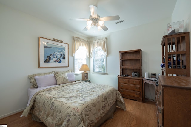 bedroom featuring ceiling fan, light wood finished floors, visible vents, and baseboards