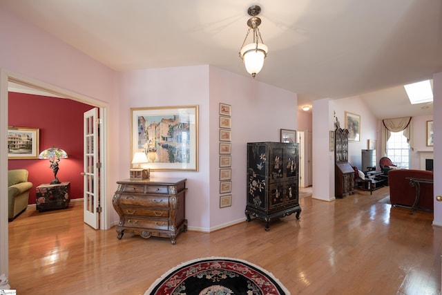 interior space with light wood-style floors, lofted ceiling with skylight, and baseboards