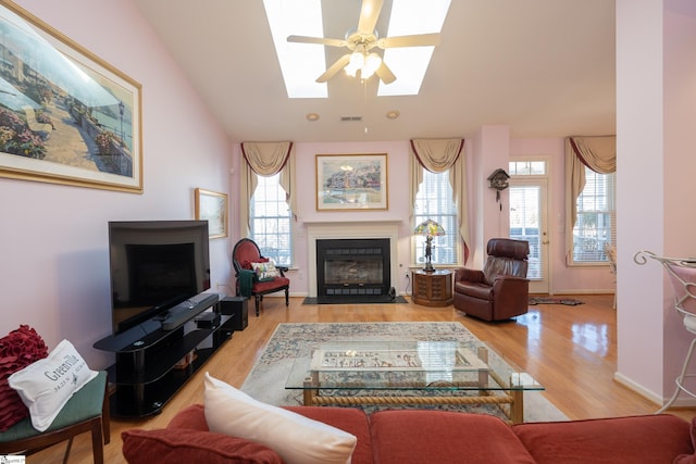 living room with a fireplace with flush hearth, a wealth of natural light, visible vents, and wood finished floors