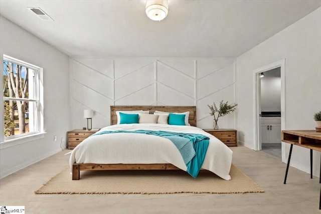 bedroom with baseboards, ensuite bath, visible vents, and light wood-style floors