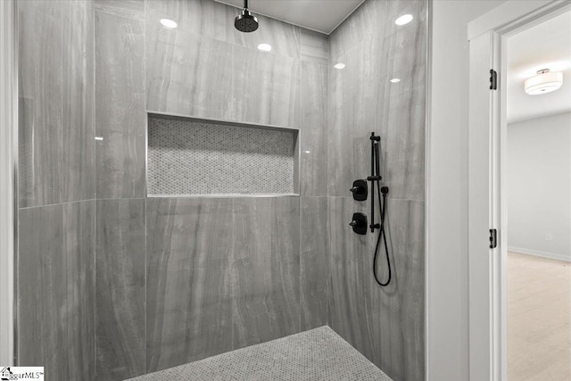 full bathroom featuring baseboards and tiled shower