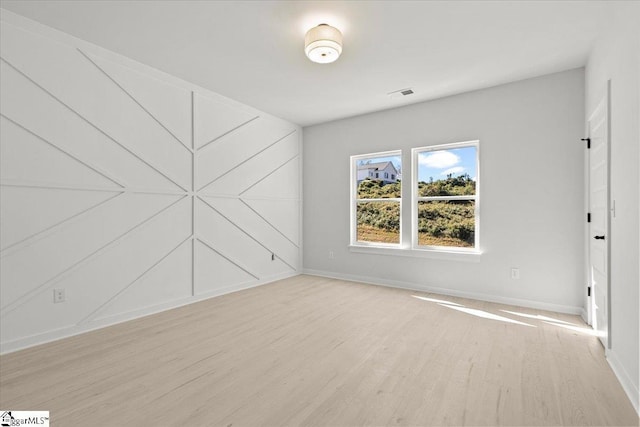 unfurnished room with light wood-type flooring, baseboards, and visible vents