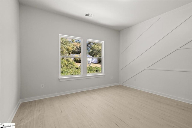 empty room featuring light wood-type flooring, visible vents, and baseboards