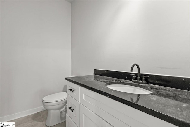 bathroom featuring toilet, tile patterned flooring, vanity, and baseboards