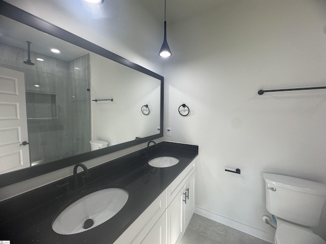 bathroom with tiled shower, a sink, toilet, and double vanity