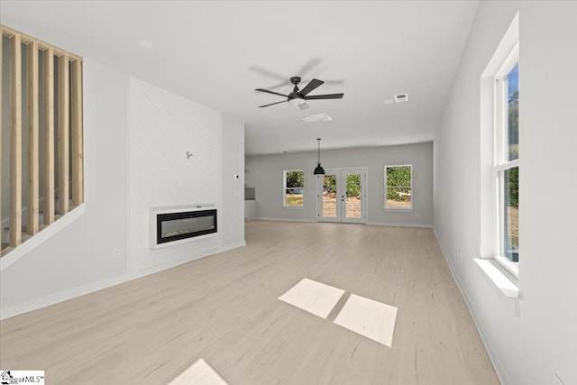 unfurnished living room with baseboards, a fireplace, visible vents, and light wood-style floors