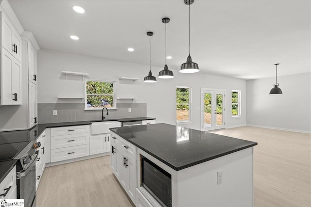 kitchen featuring electric range, light wood-style flooring, black microwave, open shelves, and a sink