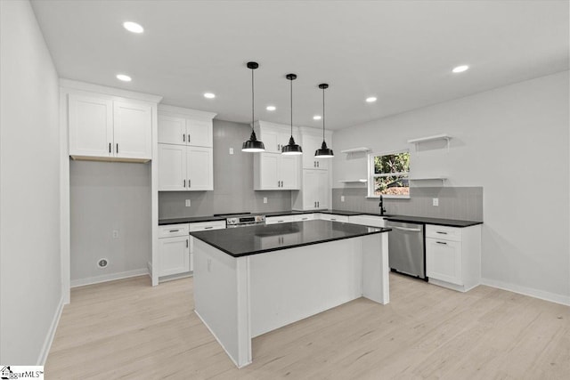 kitchen with dark countertops, light wood-style flooring, white cabinets, and stainless steel dishwasher