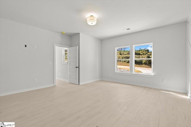 unfurnished room with light wood-style flooring, visible vents, and baseboards