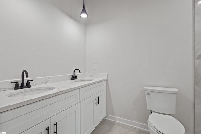 full bathroom featuring baseboards, a sink, toilet, and double vanity