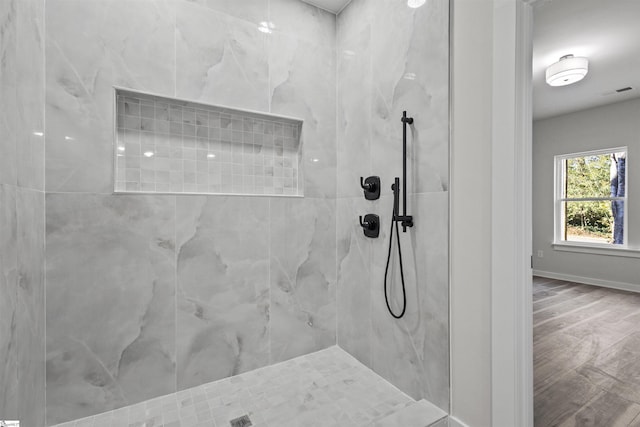 full bath with visible vents, baseboards, a tile shower, and wood finished floors