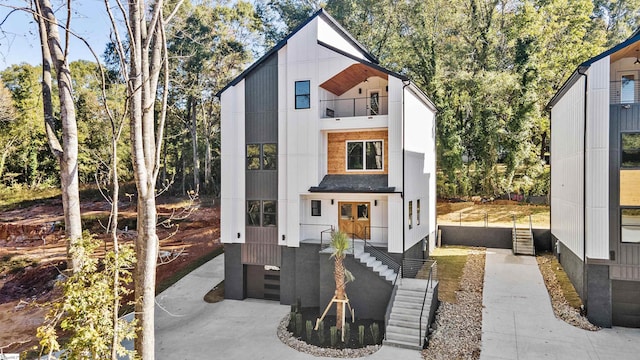 view of front of house featuring a garage, concrete driveway, and a balcony