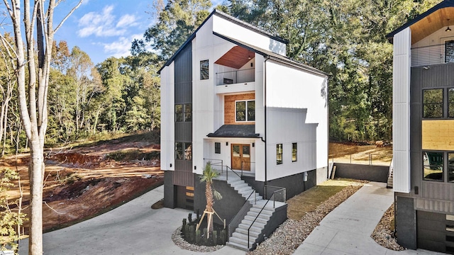 modern home featuring a garage, a balcony, and concrete driveway