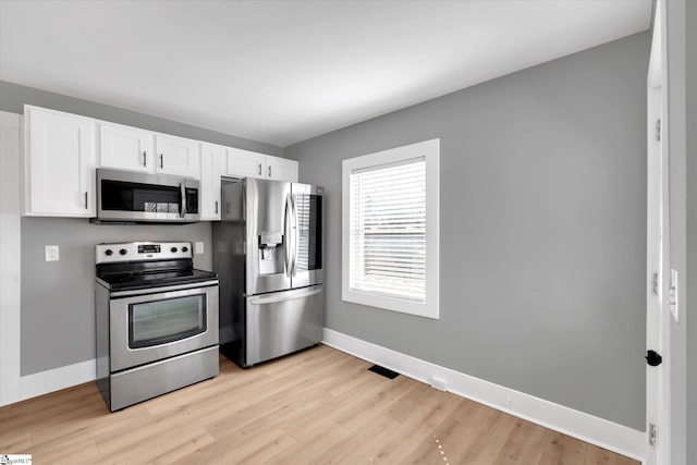 kitchen featuring baseboards, appliances with stainless steel finishes, light wood-style floors, and white cabinets