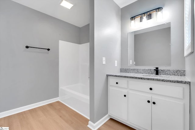 bathroom featuring tub / shower combination, vanity, baseboards, and wood finished floors