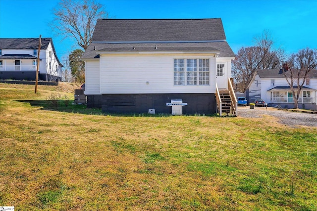 rear view of house with a shingled roof and a yard