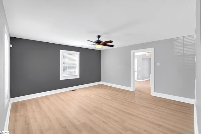 spare room featuring visible vents, light wood finished floors, a ceiling fan, and baseboards