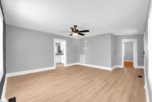 unfurnished room with visible vents, light wood finished floors, a ceiling fan, and baseboards