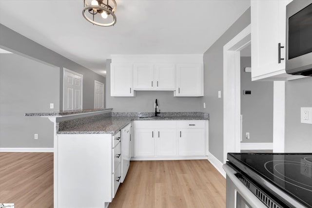 kitchen with white cabinetry, appliances with stainless steel finishes, light stone counters, and a sink