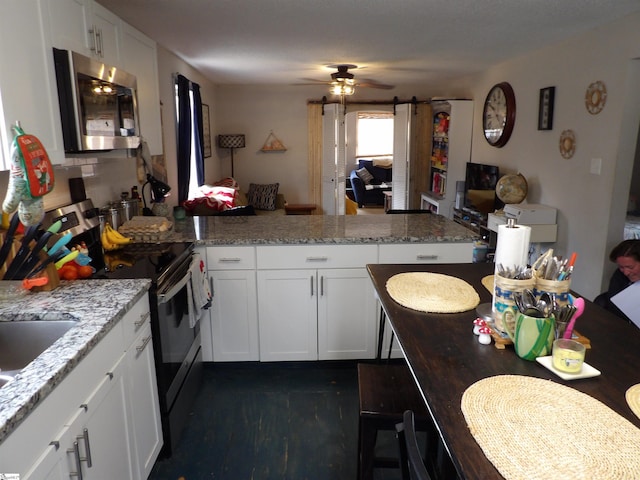 kitchen with stainless steel appliances, white cabinetry, a peninsula, and a barn door