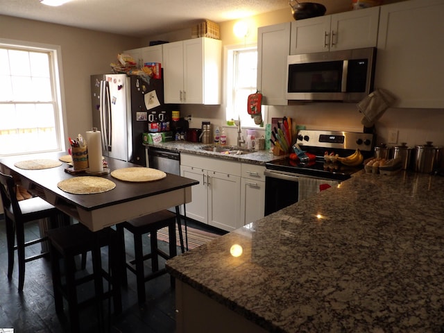 kitchen with a healthy amount of sunlight, white cabinets, stainless steel appliances, and a sink