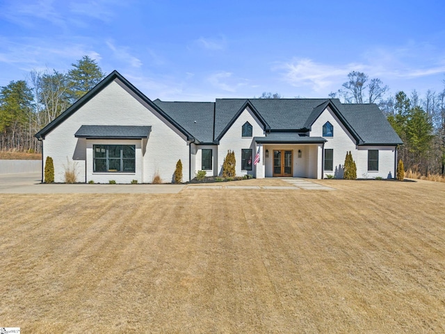 modern inspired farmhouse with french doors, a front lawn, and brick siding