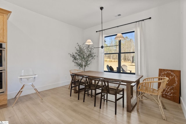 dining area featuring visible vents, light wood-style flooring, and baseboards