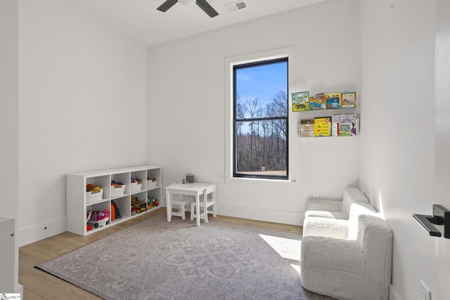 playroom featuring baseboards, ceiling fan, visible vents, and wood finished floors