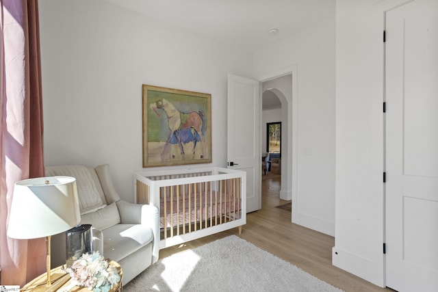 bedroom with baseboards, arched walkways, and wood finished floors