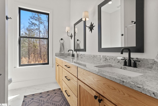 full bath with marble finish floor, double vanity, and a sink