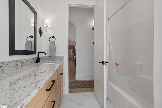 bathroom featuring marble finish floor, shower / bathtub combination with curtain, baseboards, and vanity