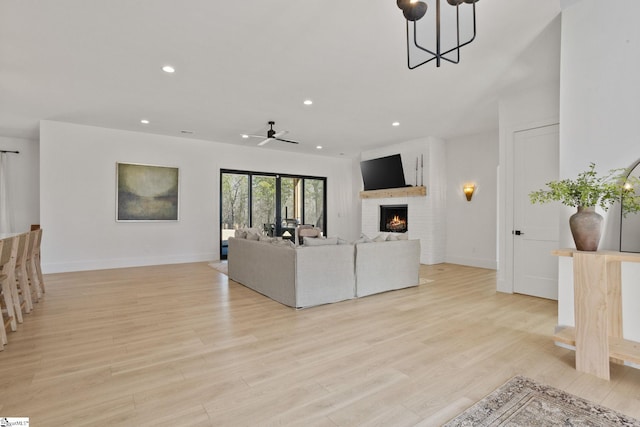 living area featuring light wood-type flooring, a fireplace, baseboards, and recessed lighting