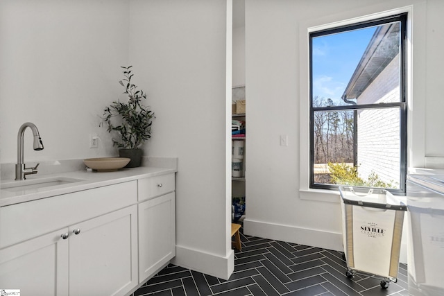 interior space featuring double vanity, baseboards, and a sink