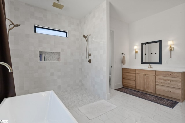 bathroom with marble finish floor, tiled shower, and vanity