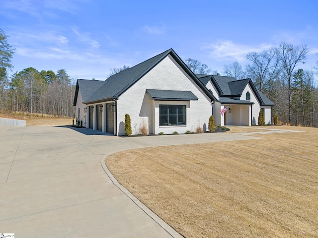 view of front of home with a front lawn, concrete driveway, and brick siding