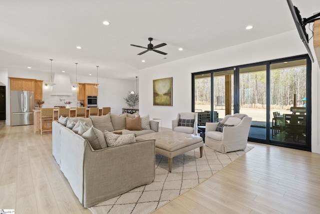 living room featuring light wood-style flooring, a ceiling fan, and recessed lighting