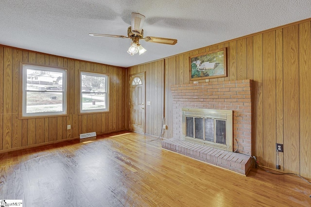 unfurnished living room with light wood-style flooring, a fireplace, visible vents, and a textured ceiling