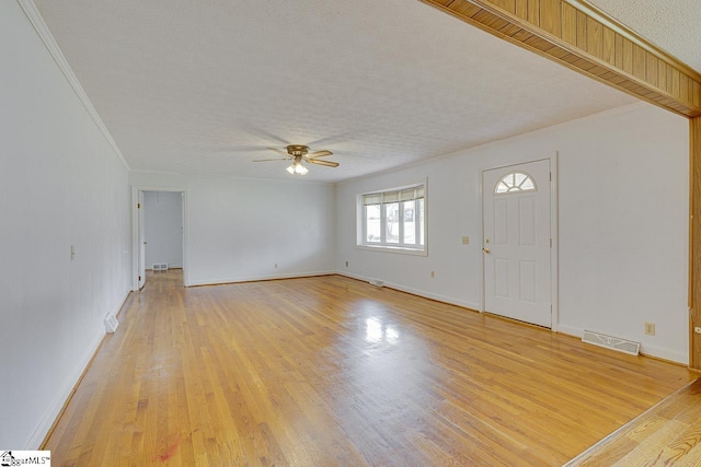 unfurnished living room with light wood-type flooring, visible vents, and crown molding