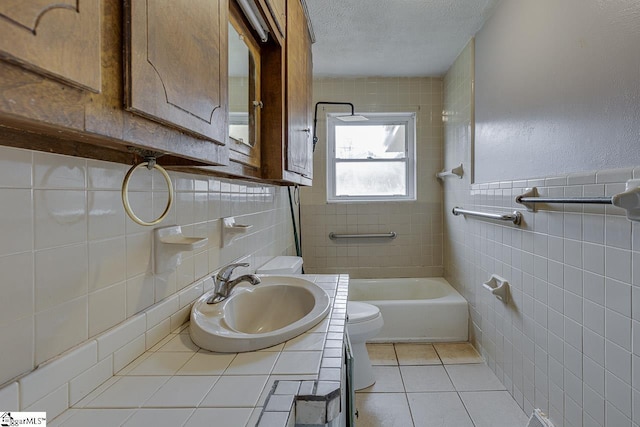 full bathroom with tile walls, toilet, vanity, a textured ceiling, and tile patterned floors